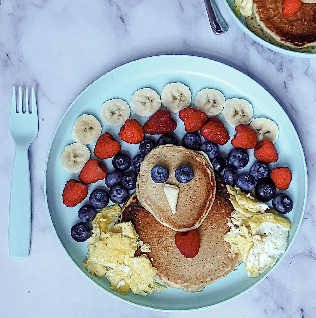 turkey shaped pancakes with fruit feathers and scrambled egg wings