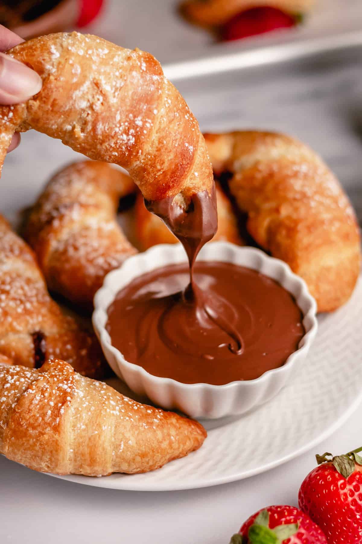 nutella crescent roll being dipped into nutella spread