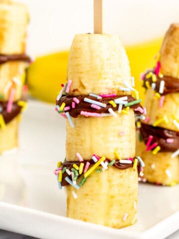 frozen banana bites with nutella and sprinkles on a white plate