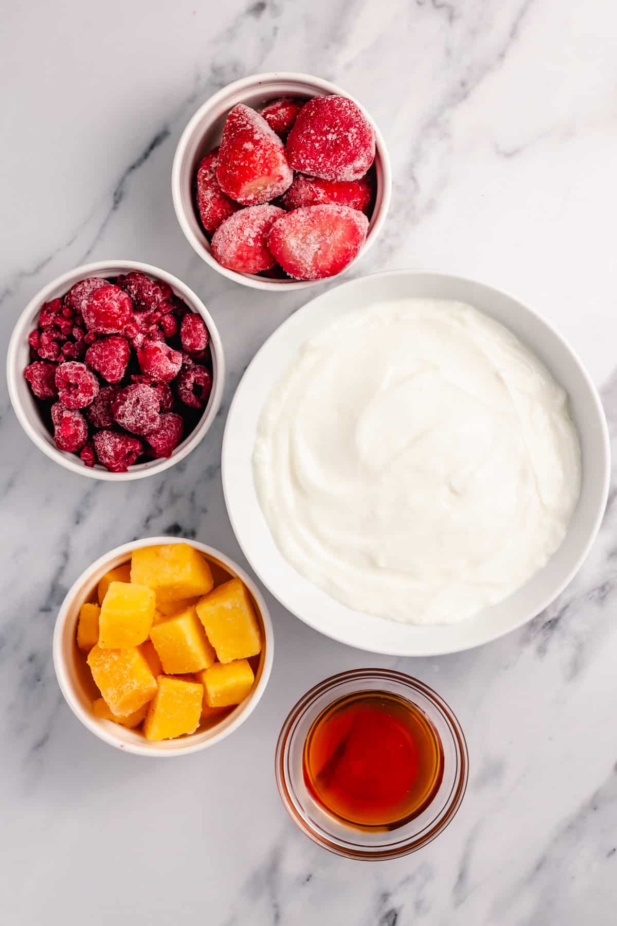 yogurt, mango, raspberry, strawberry and honey in small jars 