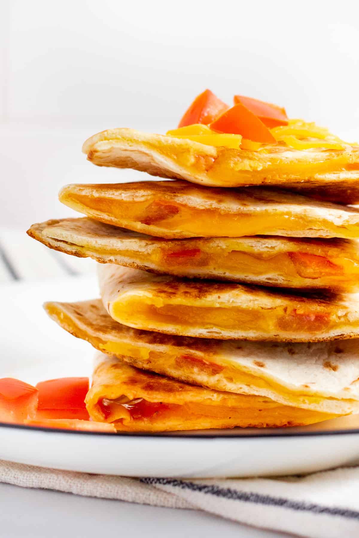 a stack of cheese and tomato quesadillas on a white plate