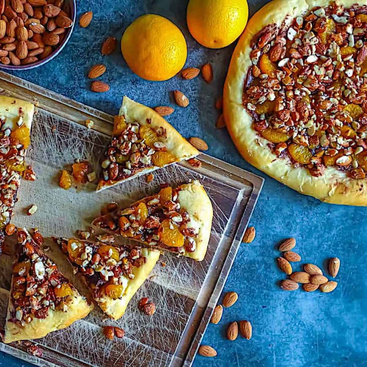 nutella dessert pizza with oranges and almonds on a cutting board