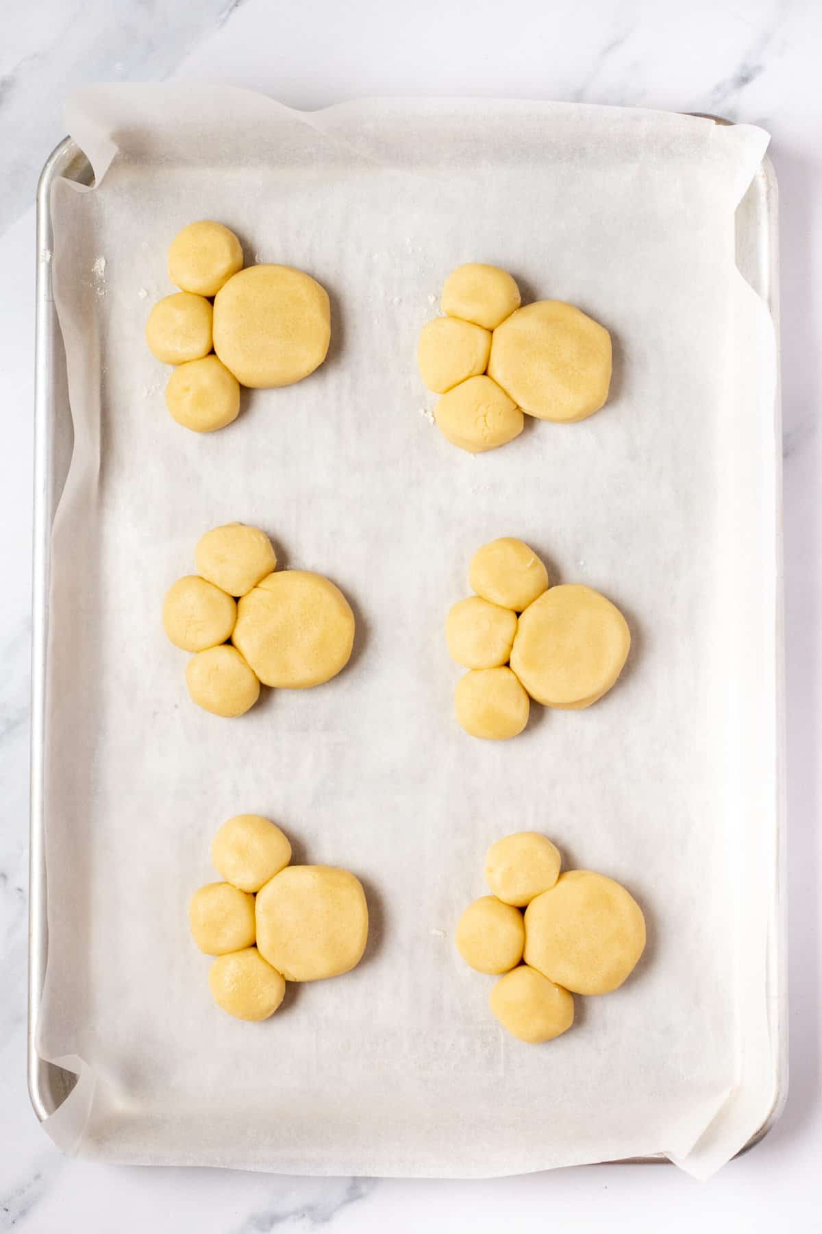bunny paw cookies unbaked on a cookie sheet