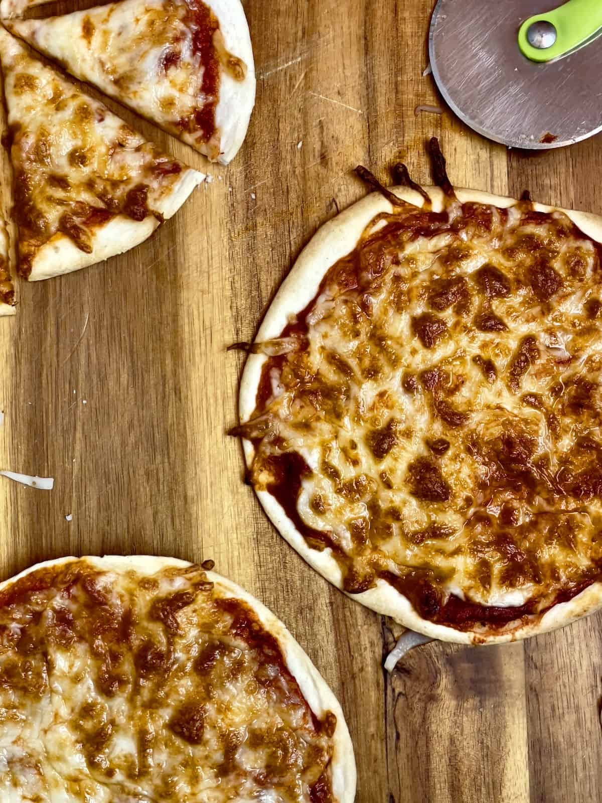 three tortilla pizzas on a cutting board