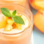 banana peach smoothie in a glass cup garnished with mint