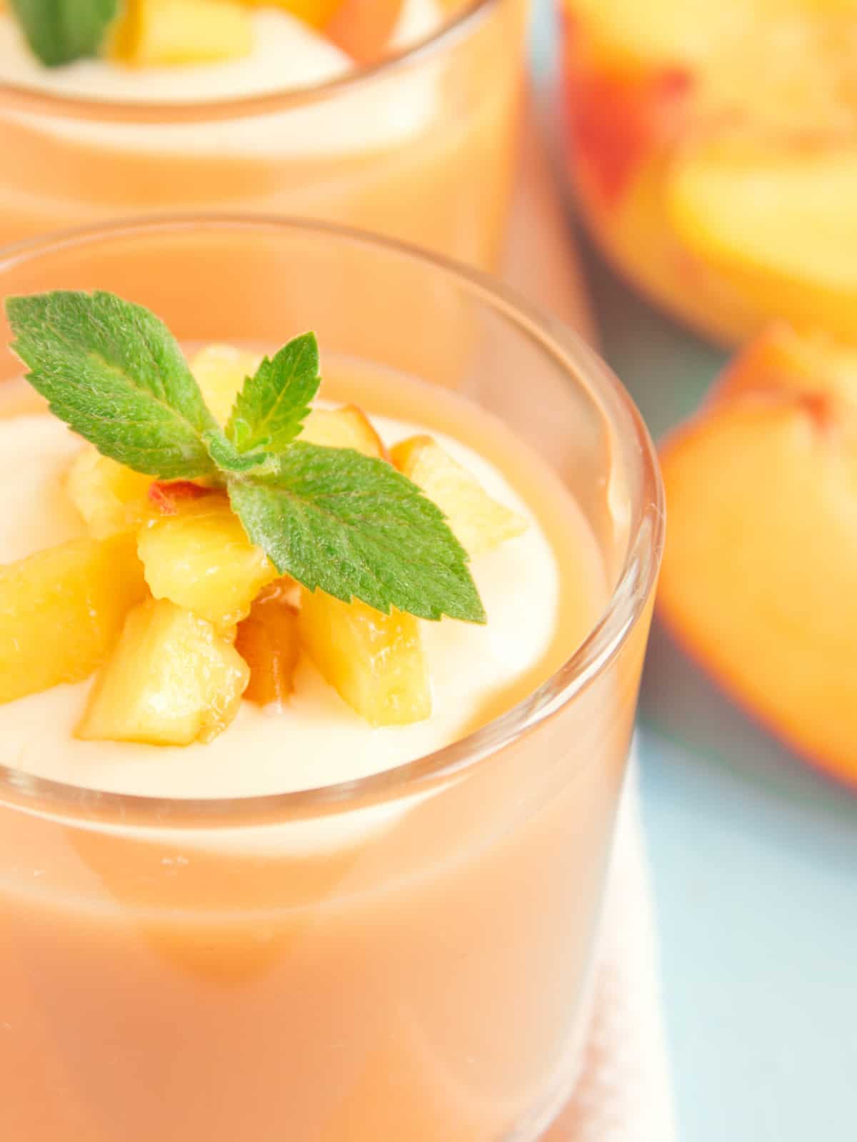banana peach smoothie in a glass cup garnished with mint