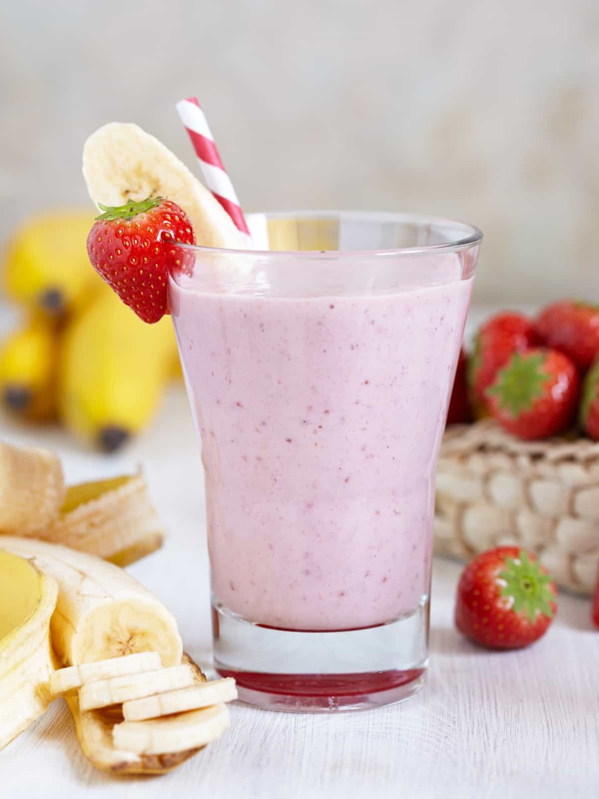 mango strawberry banana smoothie in a glass jar surrounded by fresh fruit