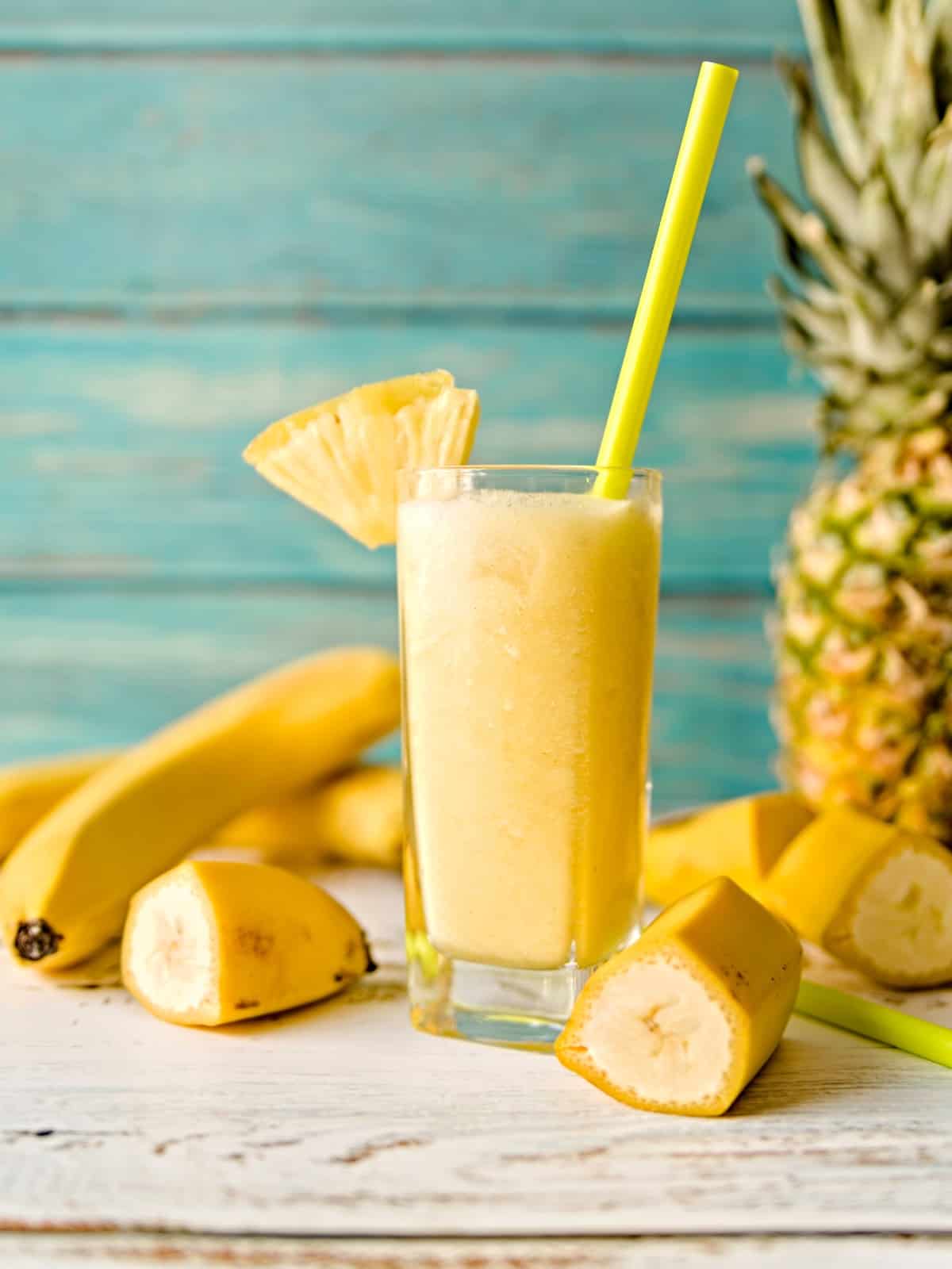 banana pineapple smoothie in a glass with sliced bananas and pineapple