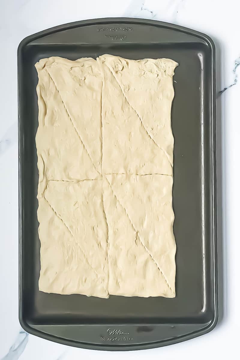 crescent dough spread onto a baking sheet