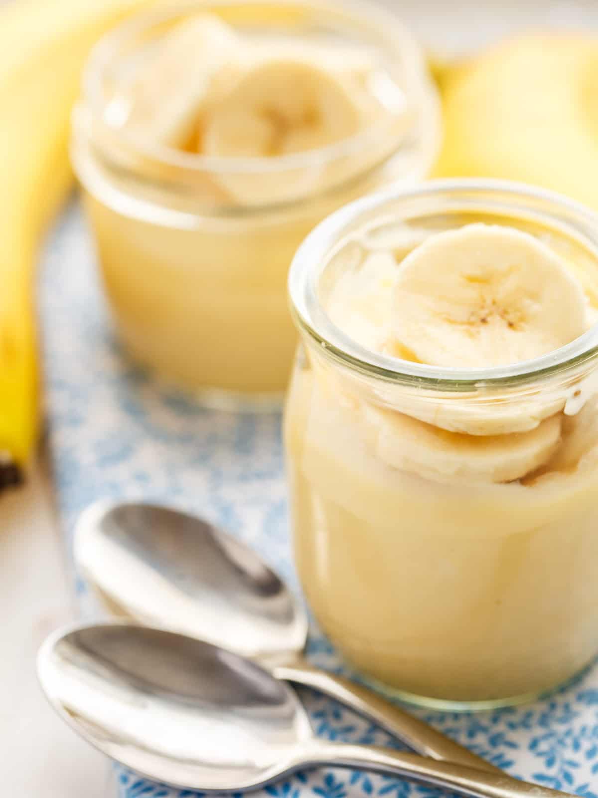 vanilla pudding topped with banana slices in a glass jar