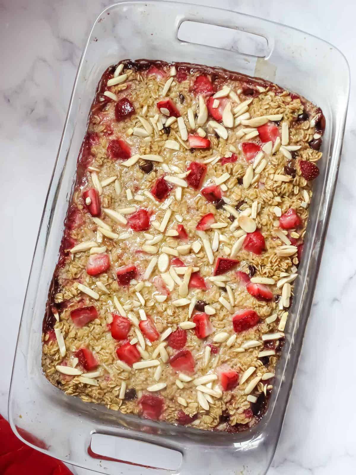 baked strawberry oatmeal in a glass baking dish on a white background