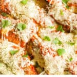 chicken tenders parmesan topped with cheese and herbs in a baking dish