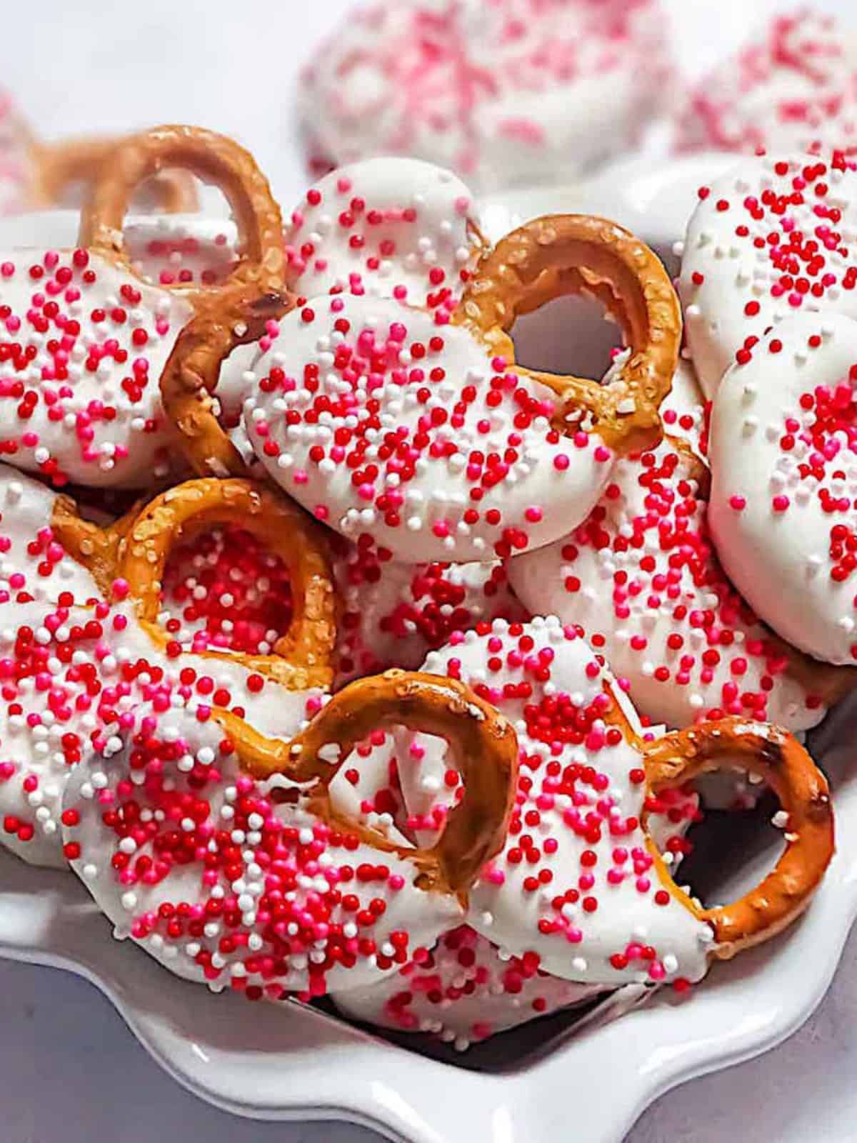 valentine's chocolate covered pretzels in a white heart shaped dish with sprinkles