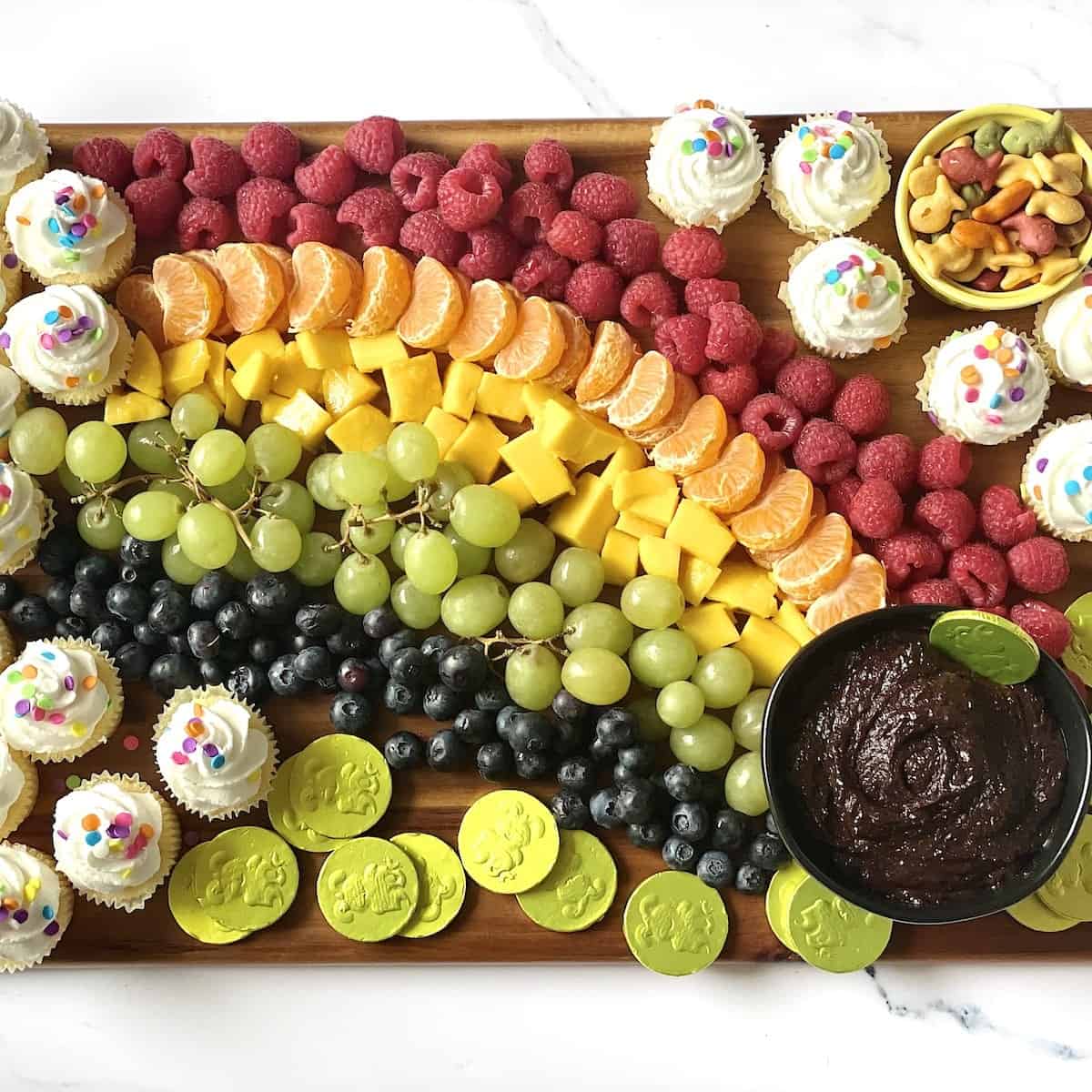 rainbow fruit tray with pot of gold and gold coins on a charcuterie board