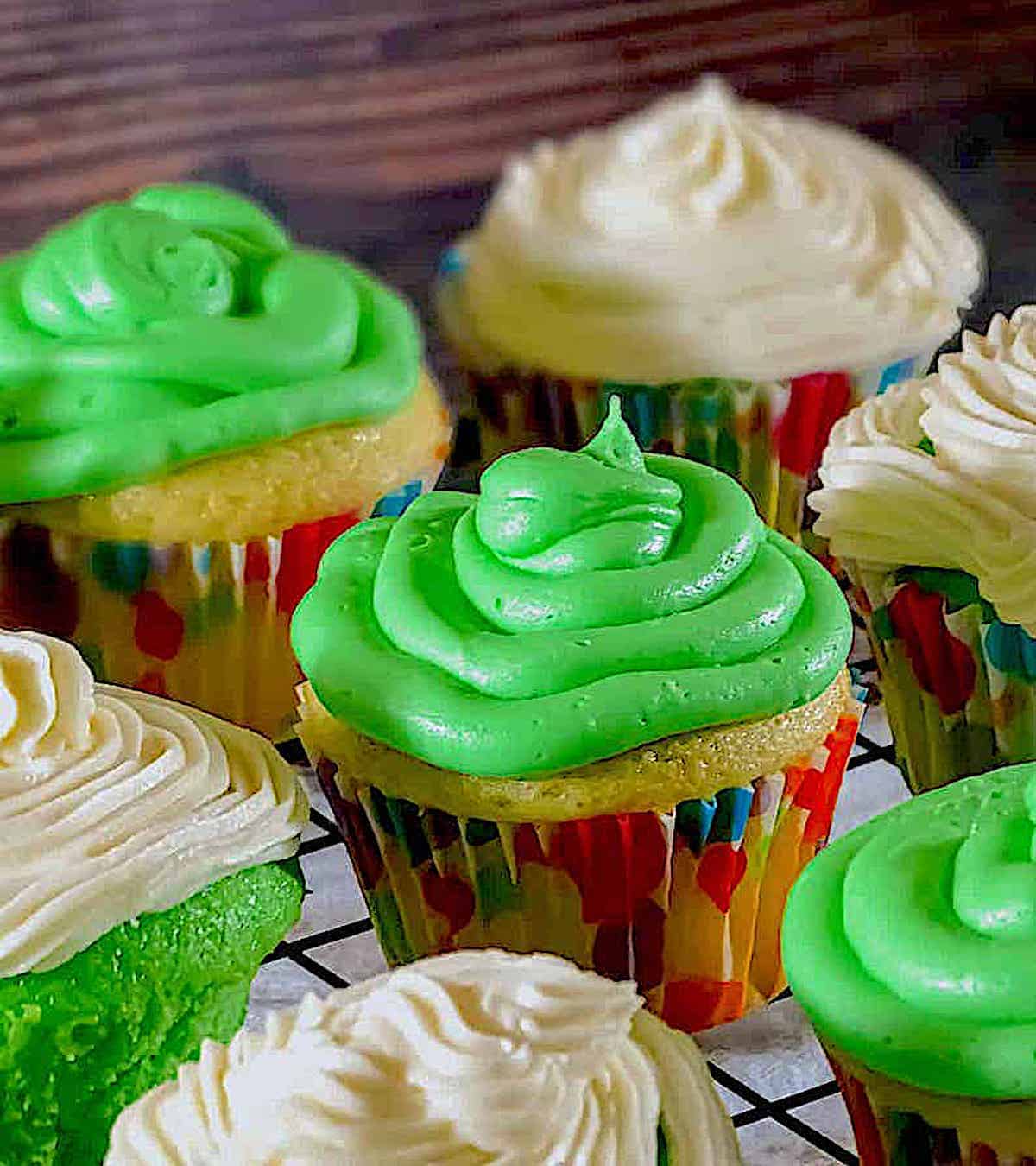 green and white frosting cupcakes in rainbow wrappers