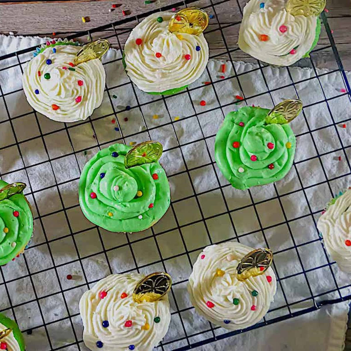 st. patrick's day cupcakes with white and green frosting and rainbow sprinkles on a cooling rack