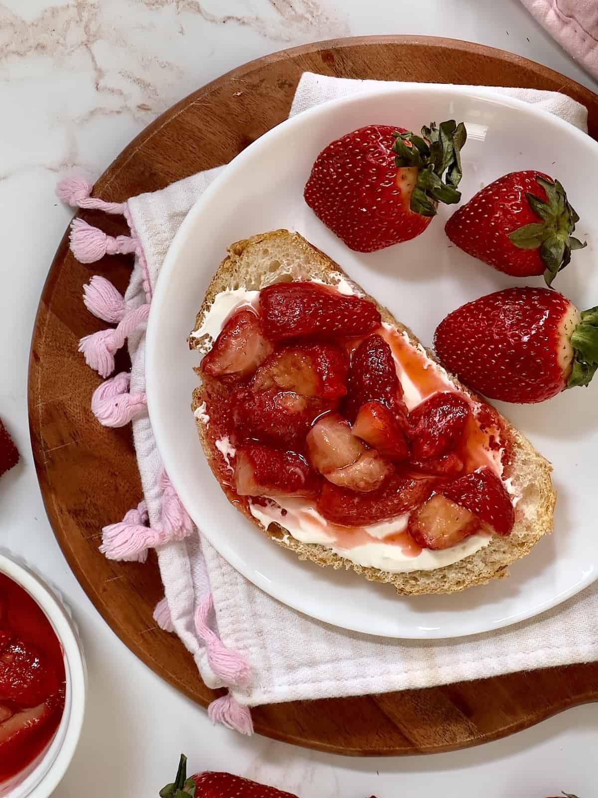 strawberry toast on a white plate with fresh strawberries 