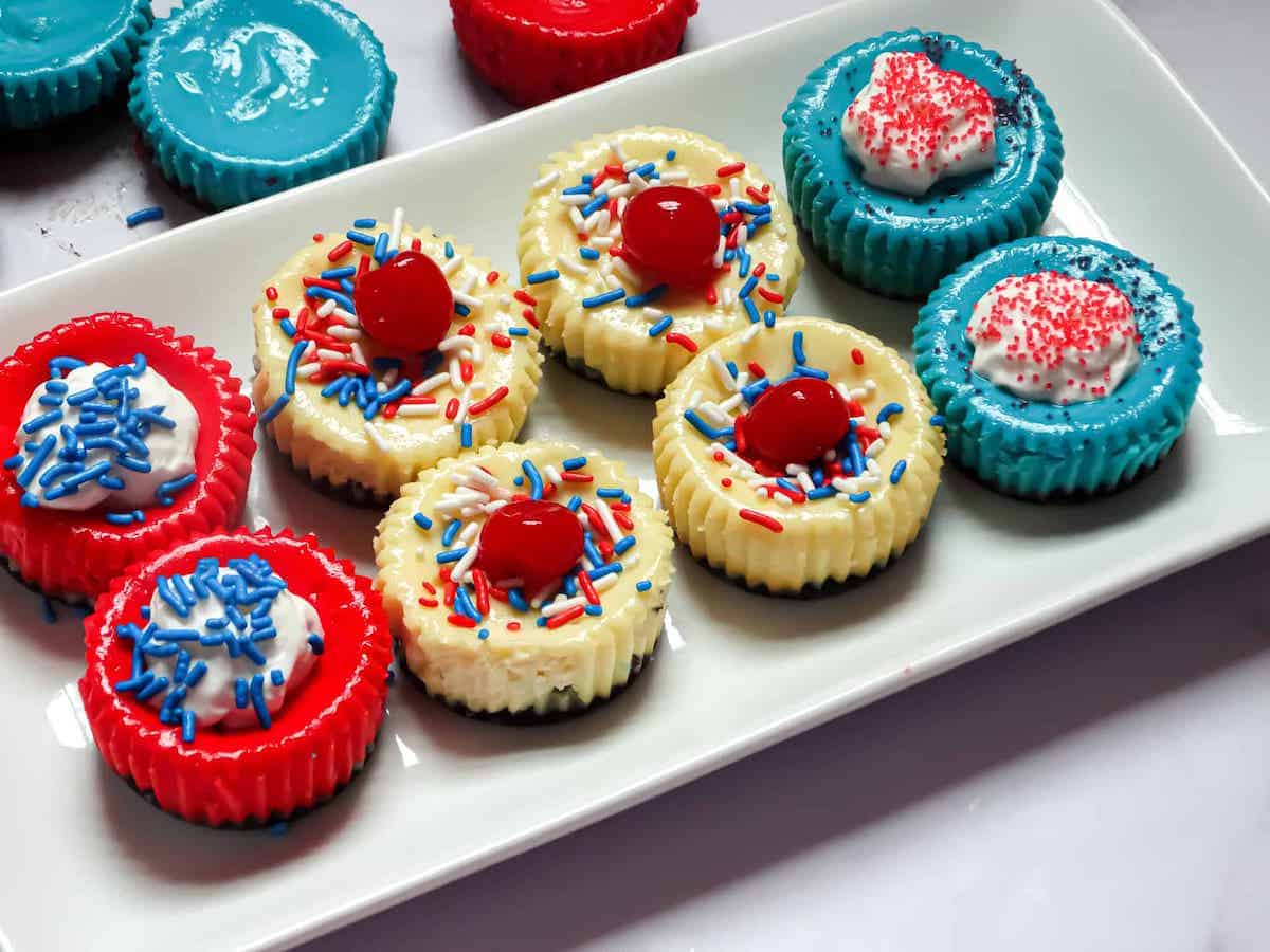 red white and blue decorated mini cheesecakes on a white plate
