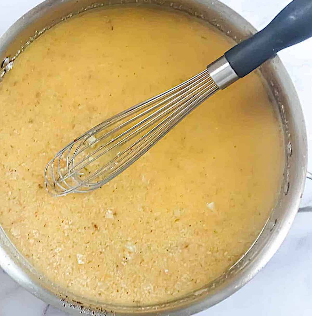 parmesan garlic sauce in a pan with a whisk