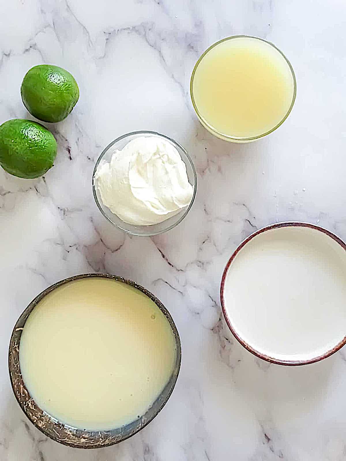 limes, coconut milk, sour cream butter and condensed milk on a table