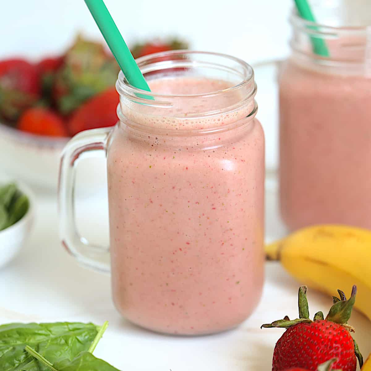 strawberry banana spinach smoothie in a glass mason jar