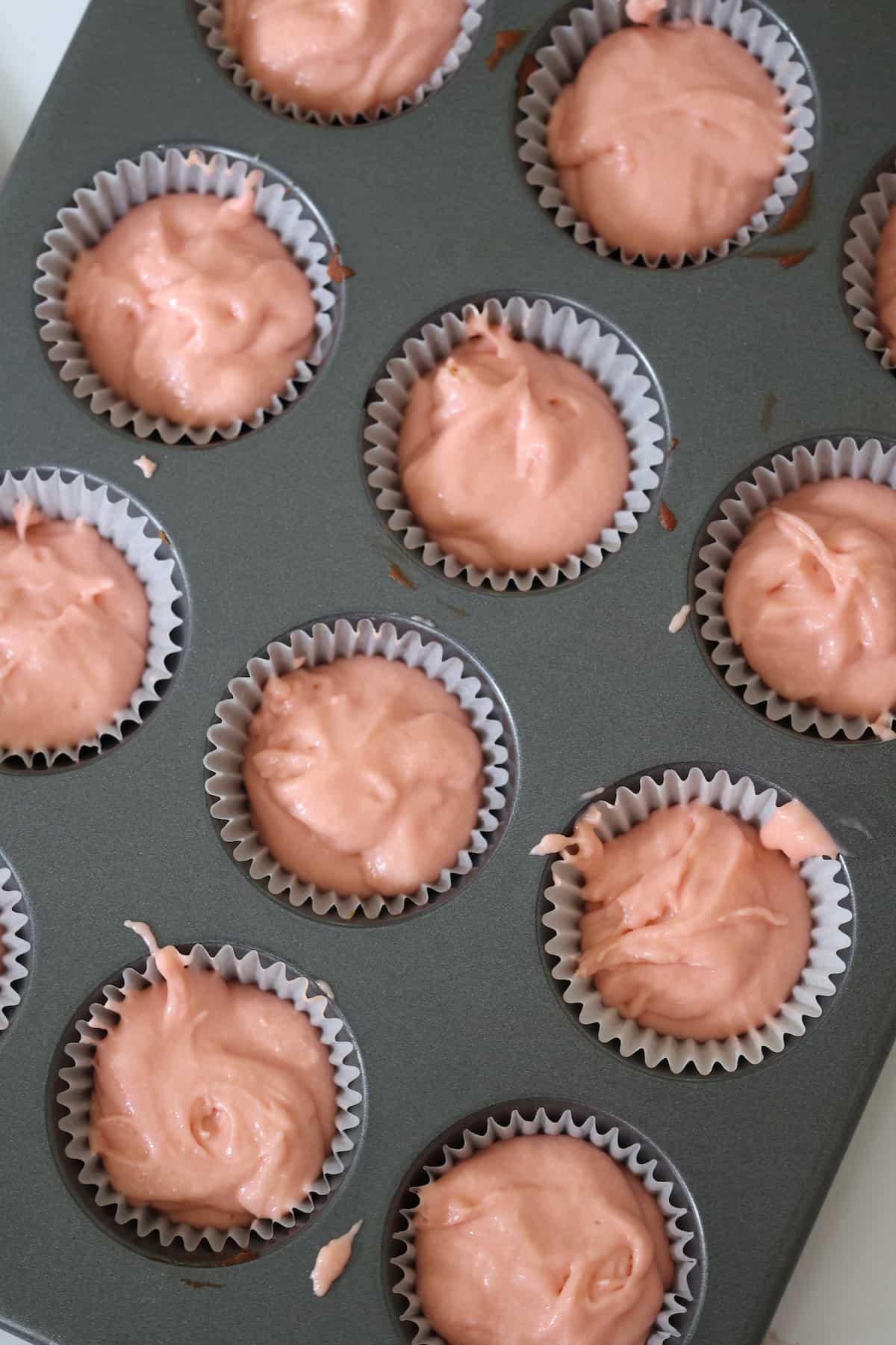 strawberry cupcake batter uncooked in a muffin pan