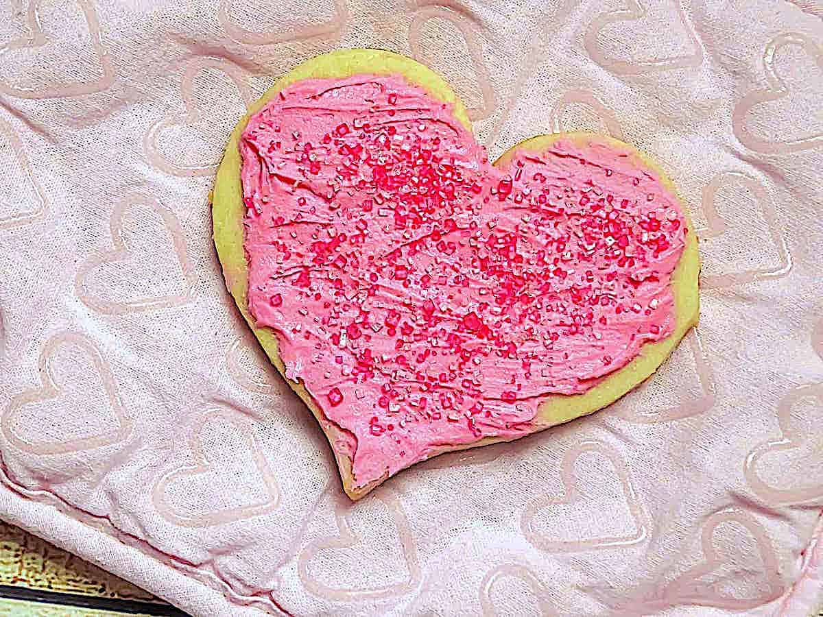 a heart cookie with pink icing and sprinkles
