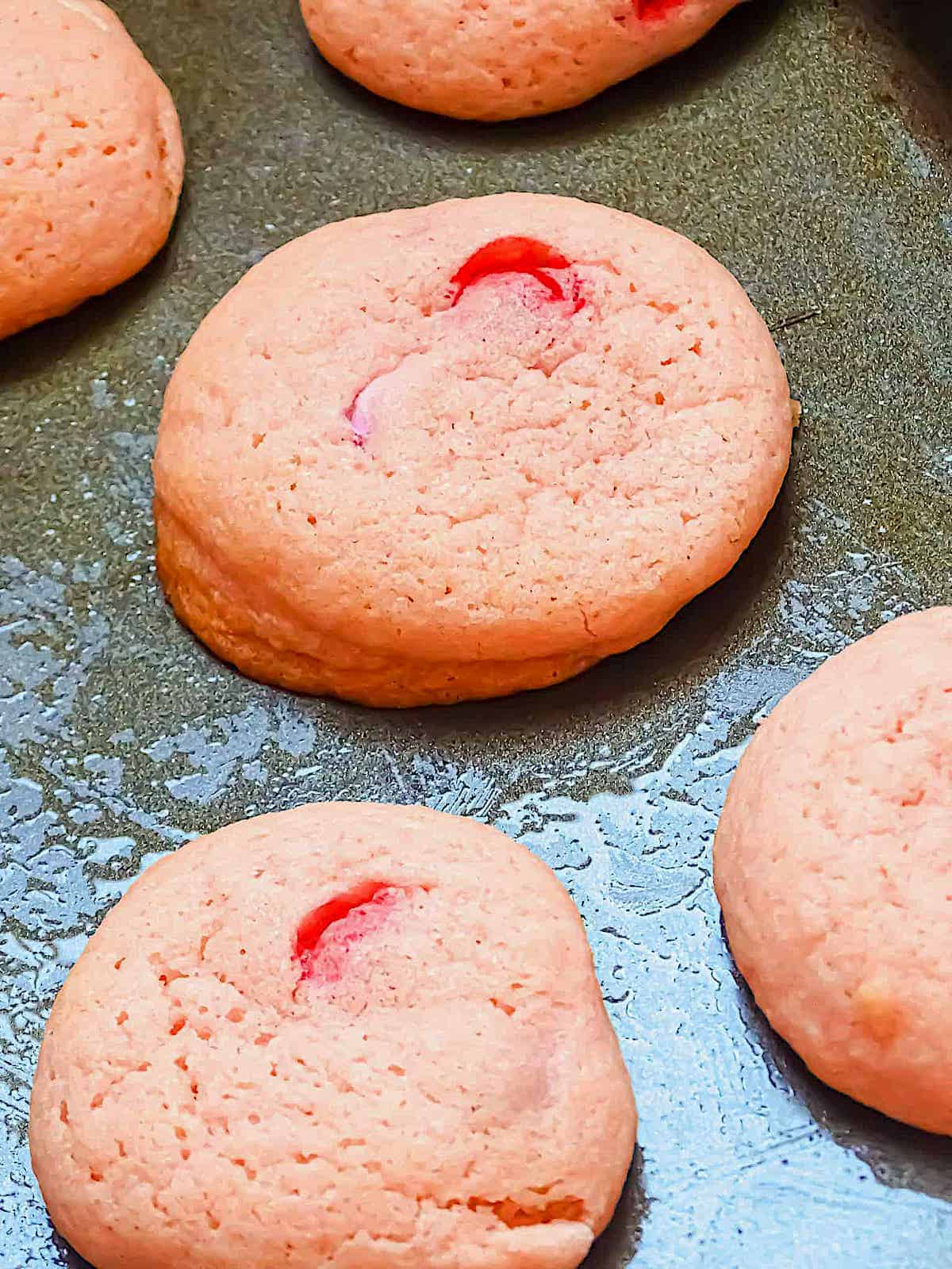 soft pink sugar cookies on a baking sheet
