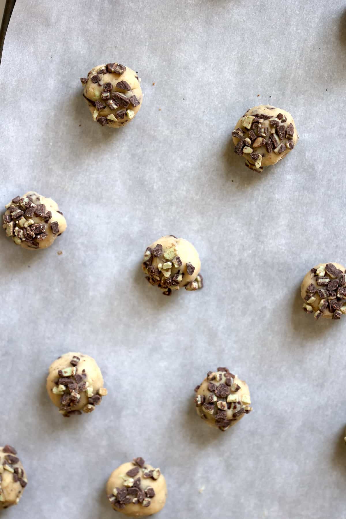 mint chocolate chip cookie dough balls on a baking sheet