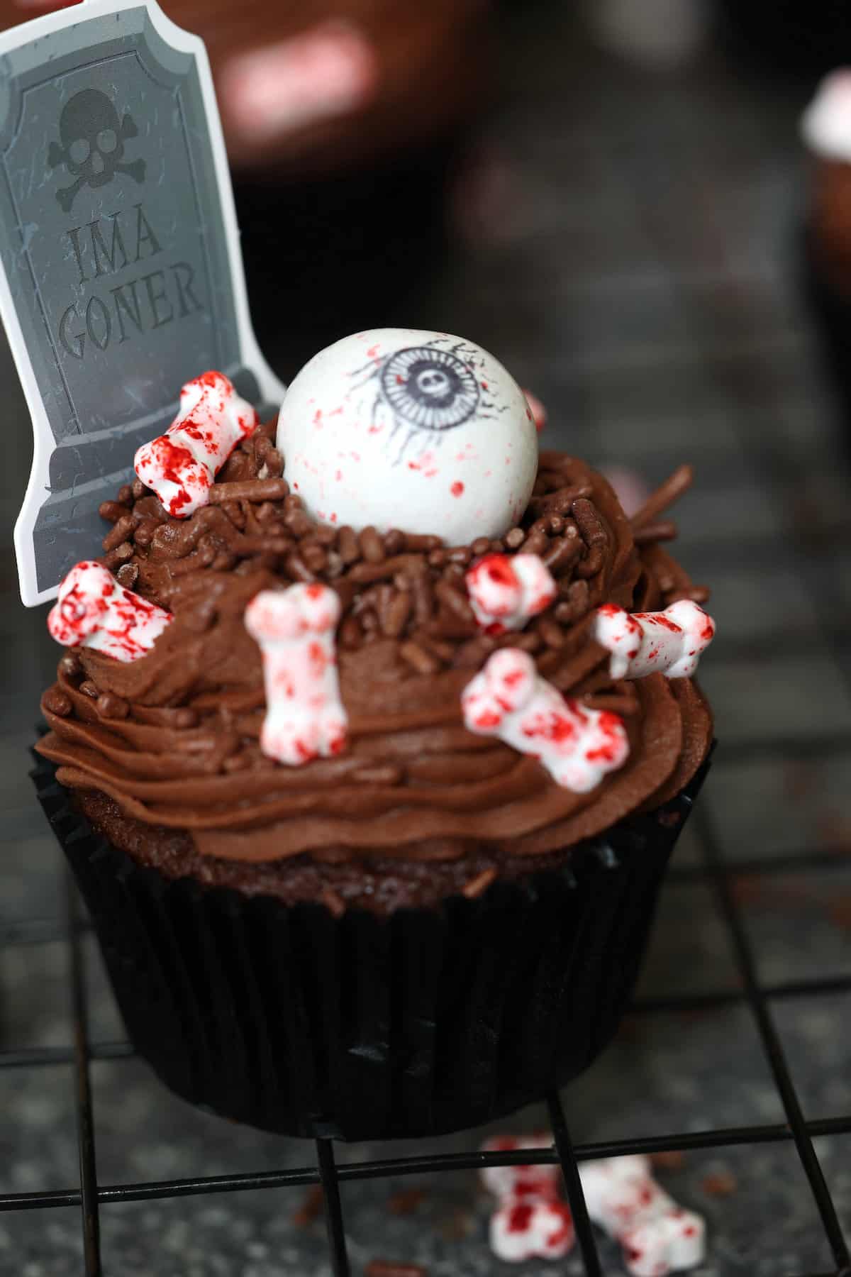 a chocolate cupcake with candy bones and a giant candy eyeball