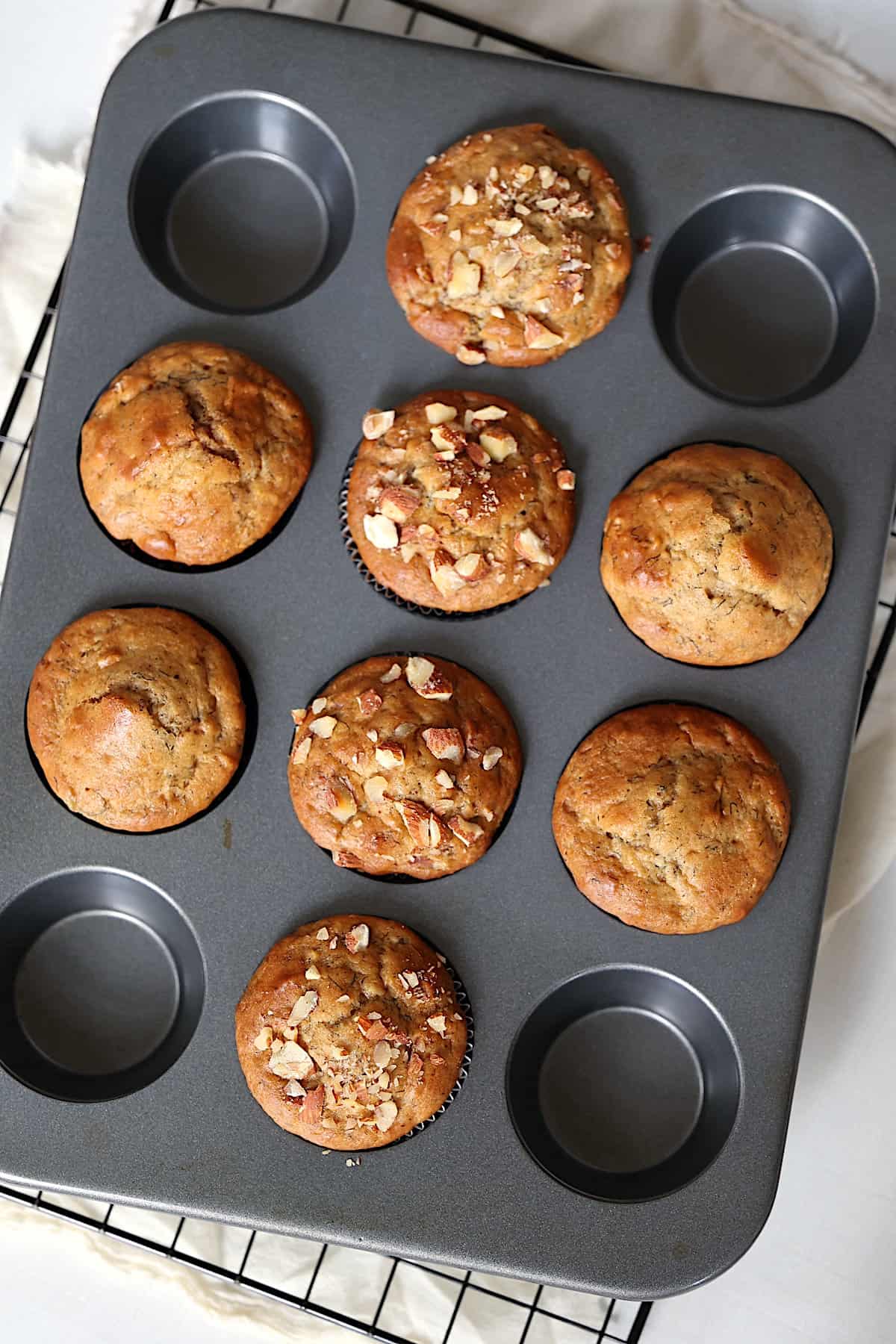 almond butter muffins topped with chopped almonds in a muffin tin