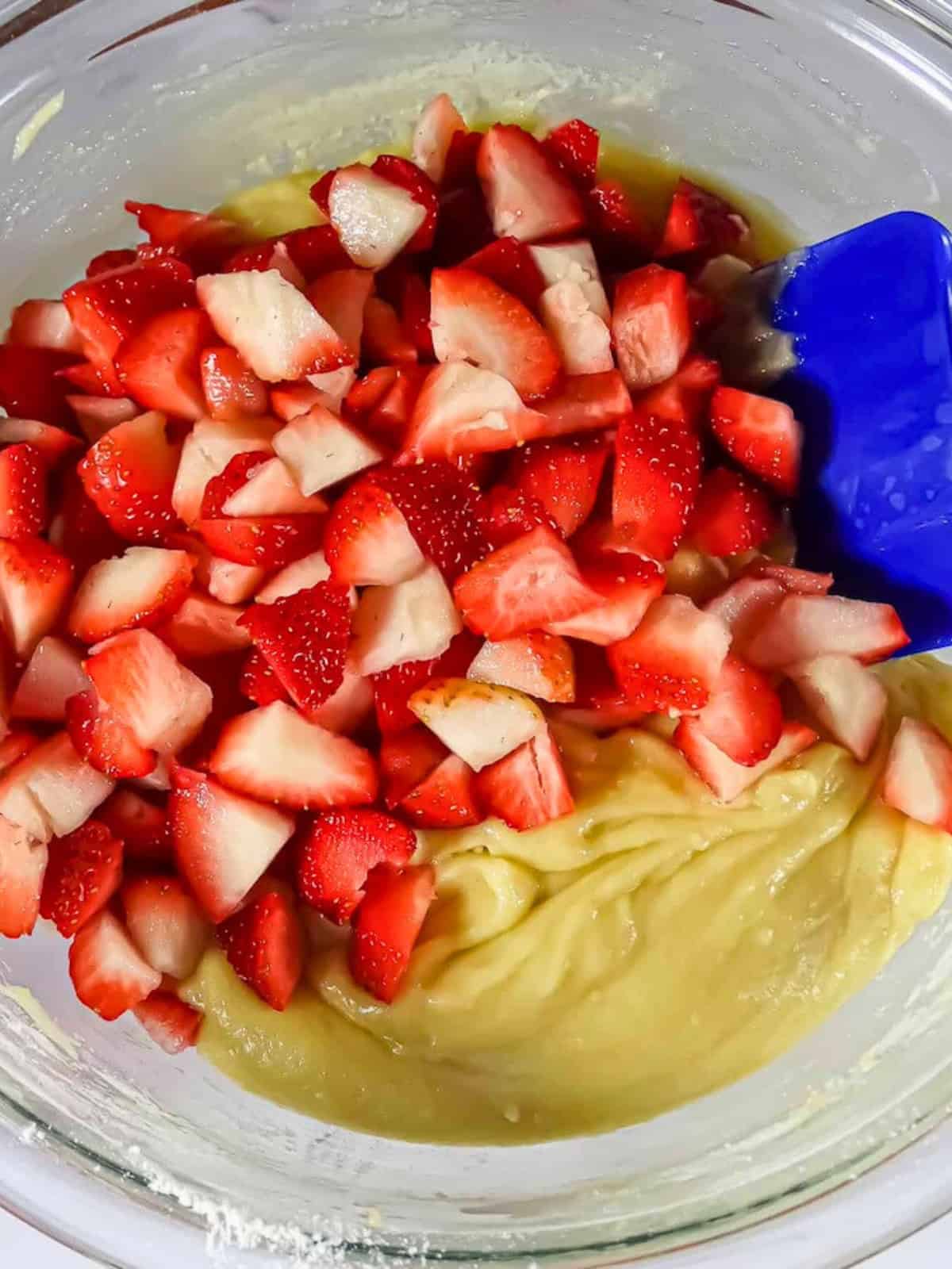 strawberries and muffin batter in a mixing bowl