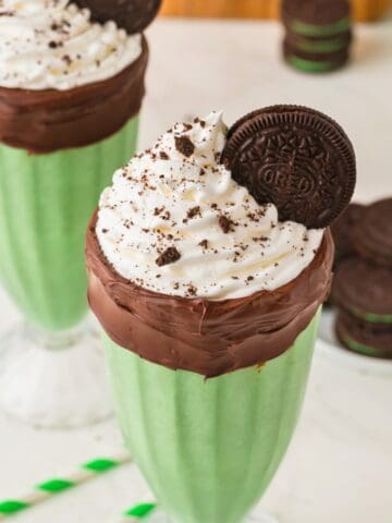 oreo mint milkshake in a milkshake glass lined with chocolate
