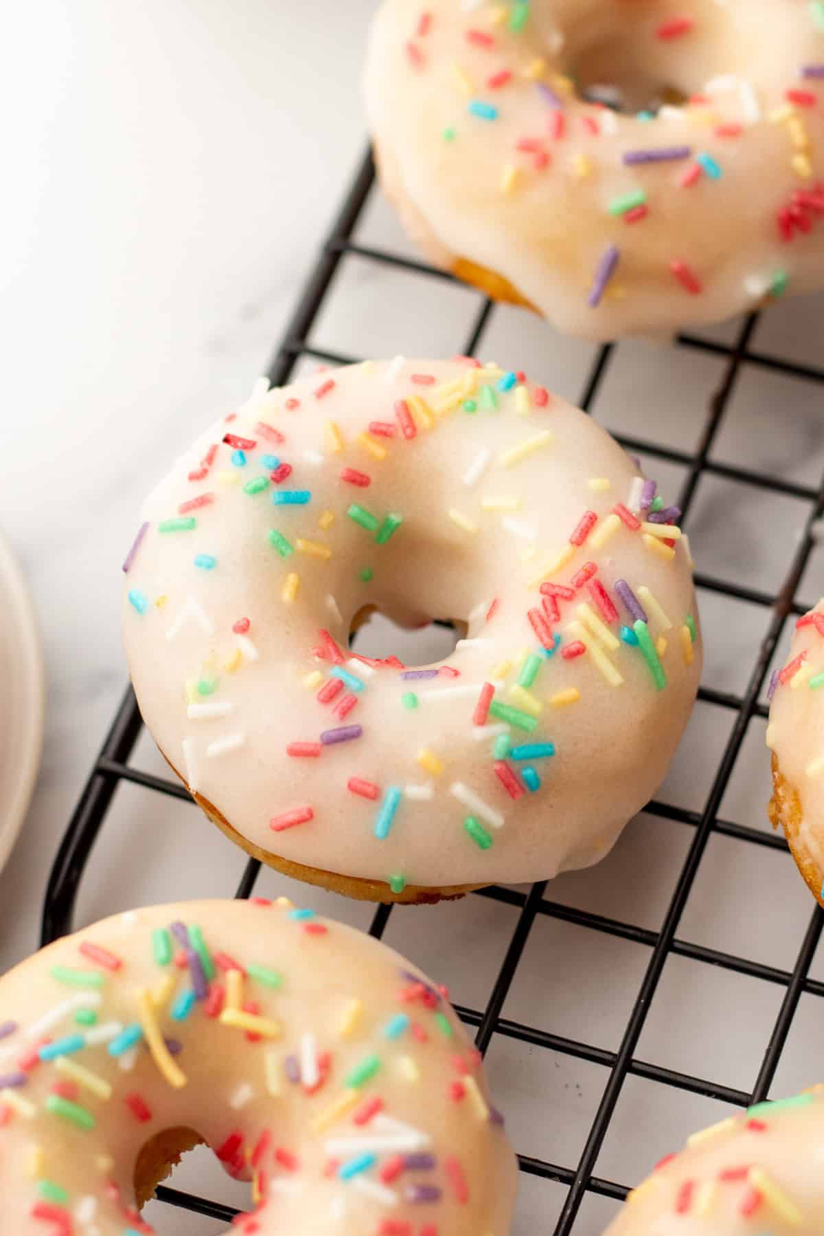 baked vanilla donut with glaze and rainbow sprinkles