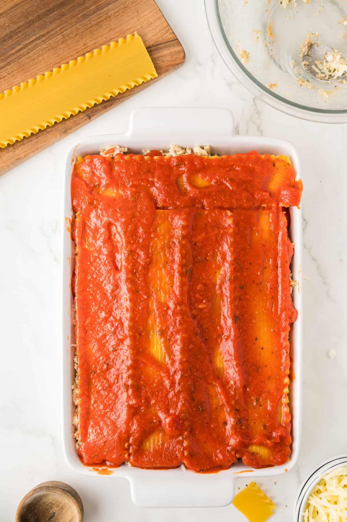 sauce layered over lasagna noodles in a baking dish