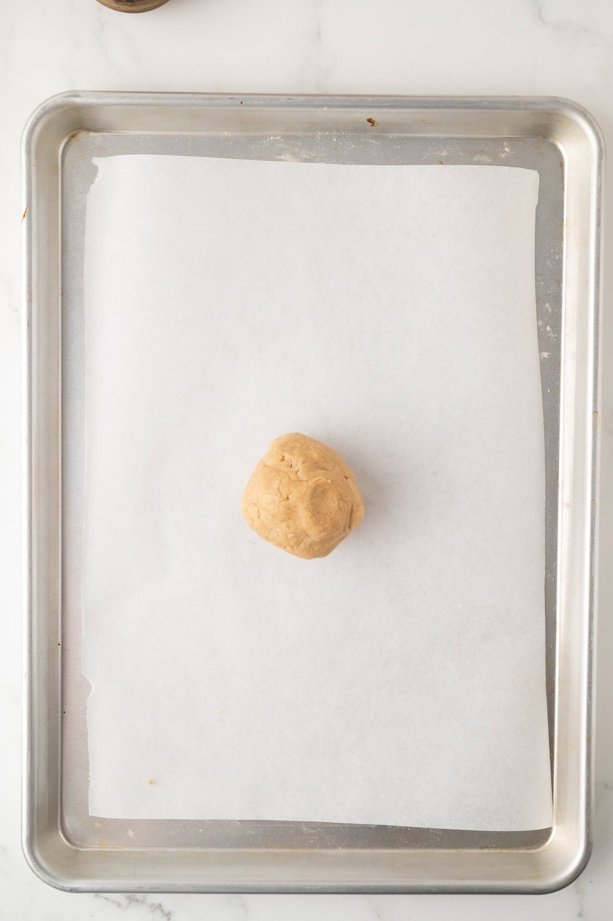 peanut butter cookie dough ball on a baking sheet