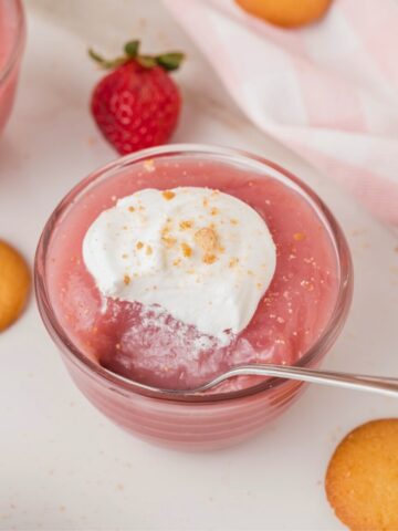 strawberry pudding topped with whipped cream in a glass