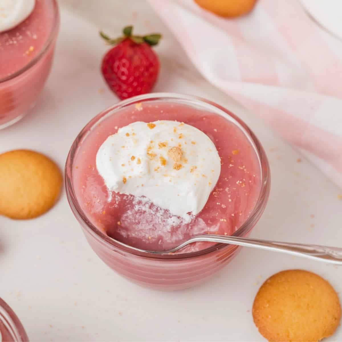 strawberry pudding topped with whipped cream in a glass